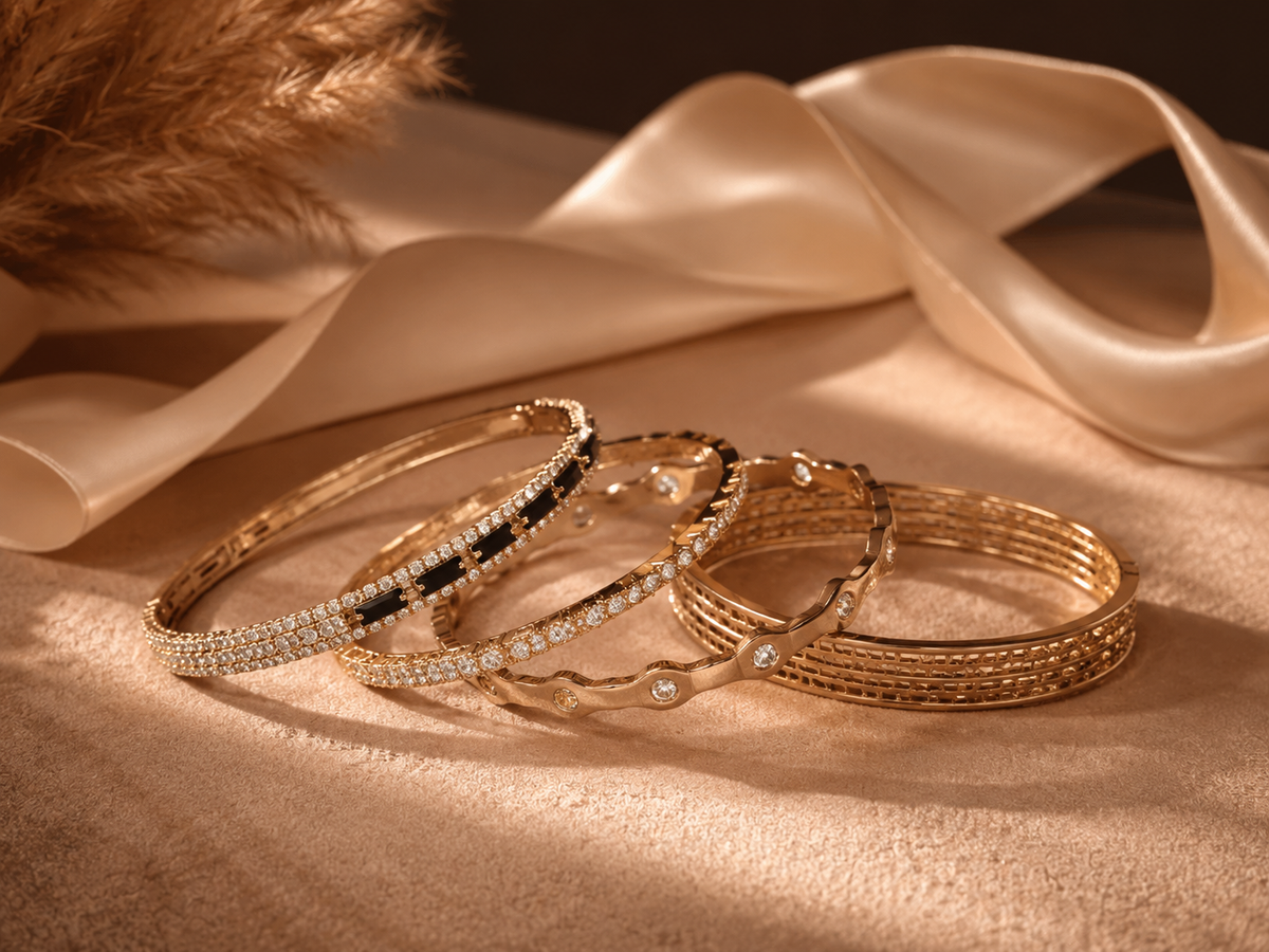 Gold bangles set with stones, stacked on almond velvet.